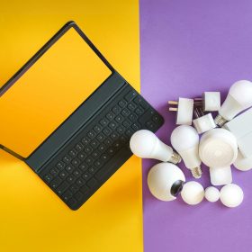 Flat lay of smart home gadgets and a keyboard on vibrant background depicting modern technology.