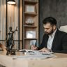 A focused lawyer in an office setting writing and reviewing legal documents, symbolizing expertise and professionalism.