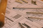 Detailed woodworking tools and instructions on a desk in a workshop, showcasing carpentry essentials.