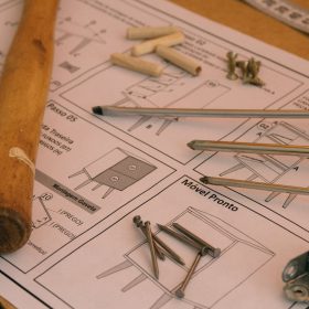 Detailed woodworking tools and instructions on a desk in a workshop, showcasing carpentry essentials.