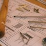 Detailed woodworking tools and instructions on a desk in a workshop, showcasing carpentry essentials.