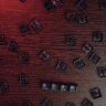 Scattered keyboard keys spelling 'SCAM' on a red-lit wooden surface, symbolizing online fraud.