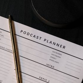 Vertical shot of a podcast planner and pen on a dark table, ideal for business and planning concepts.