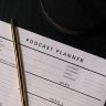 Vertical shot of a podcast planner and pen on a dark table, ideal for business and planning concepts.