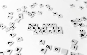 Scrabble tiles spell out 'All You Need Is Coffee' on a white background, offering a creative still life.
