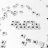 Scrabble tiles spell out 'All You Need Is Coffee' on a white background, offering a creative still life.
