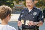 A friendly police officer shows a badge to a young boy in a community setting.
