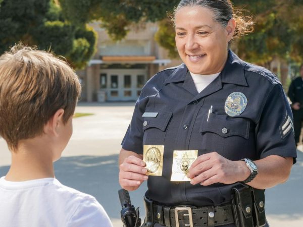A friendly police officer shows a badge to a young boy in a community setting.