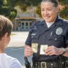 A friendly police officer shows a badge to a young boy in a community setting.