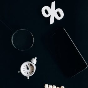 Stylish composition of clock, symbols, and text representing financial change on a dark background.