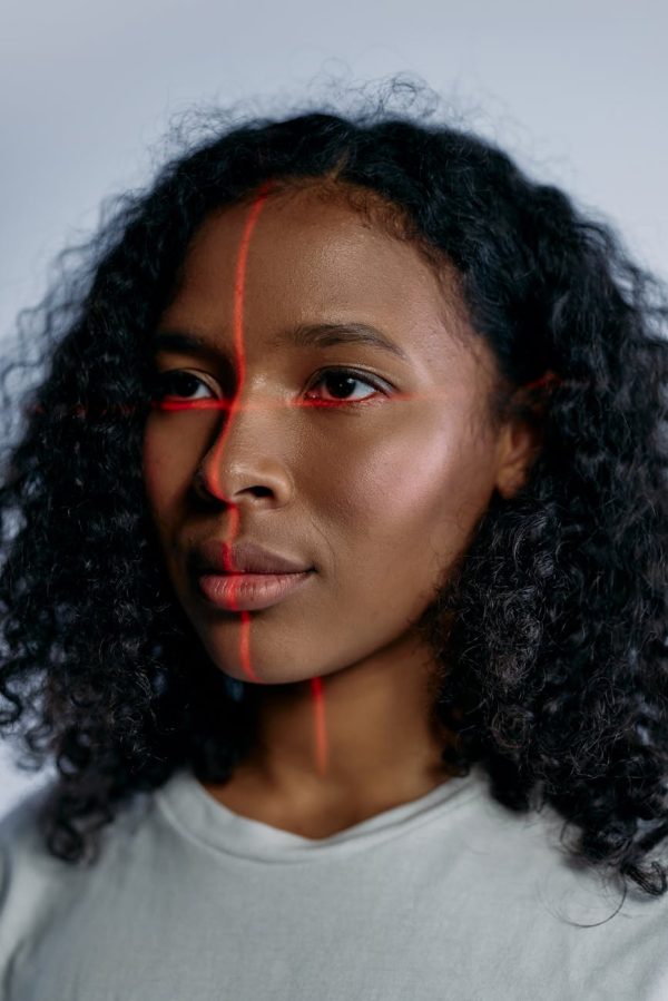 Close-up portrait of a black woman with laser scanning lines on her face, symbolizing advanced technology.
