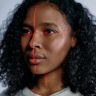 Close-up portrait of a black woman with laser scanning lines on her face, symbolizing advanced technology.
