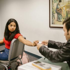 Two students seen exchanging notes in a classroom scenario during an exam.