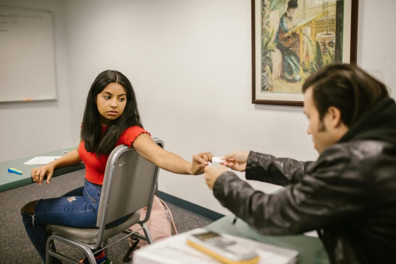 Two students seen exchanging notes in a classroom scenario during an exam.