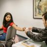 Two students seen exchanging notes in a classroom scenario during an exam.
