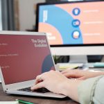 Laptop user typing with digital evolution concept on screen in a modern office environment.