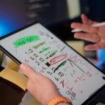 A person managing tasks on a tablet with a digital pen in a modern office setting.
