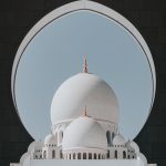 Elegant view of the Sheikh Zayed Grand Mosque dome framed by an arch in Abu Dhabi, UAE.