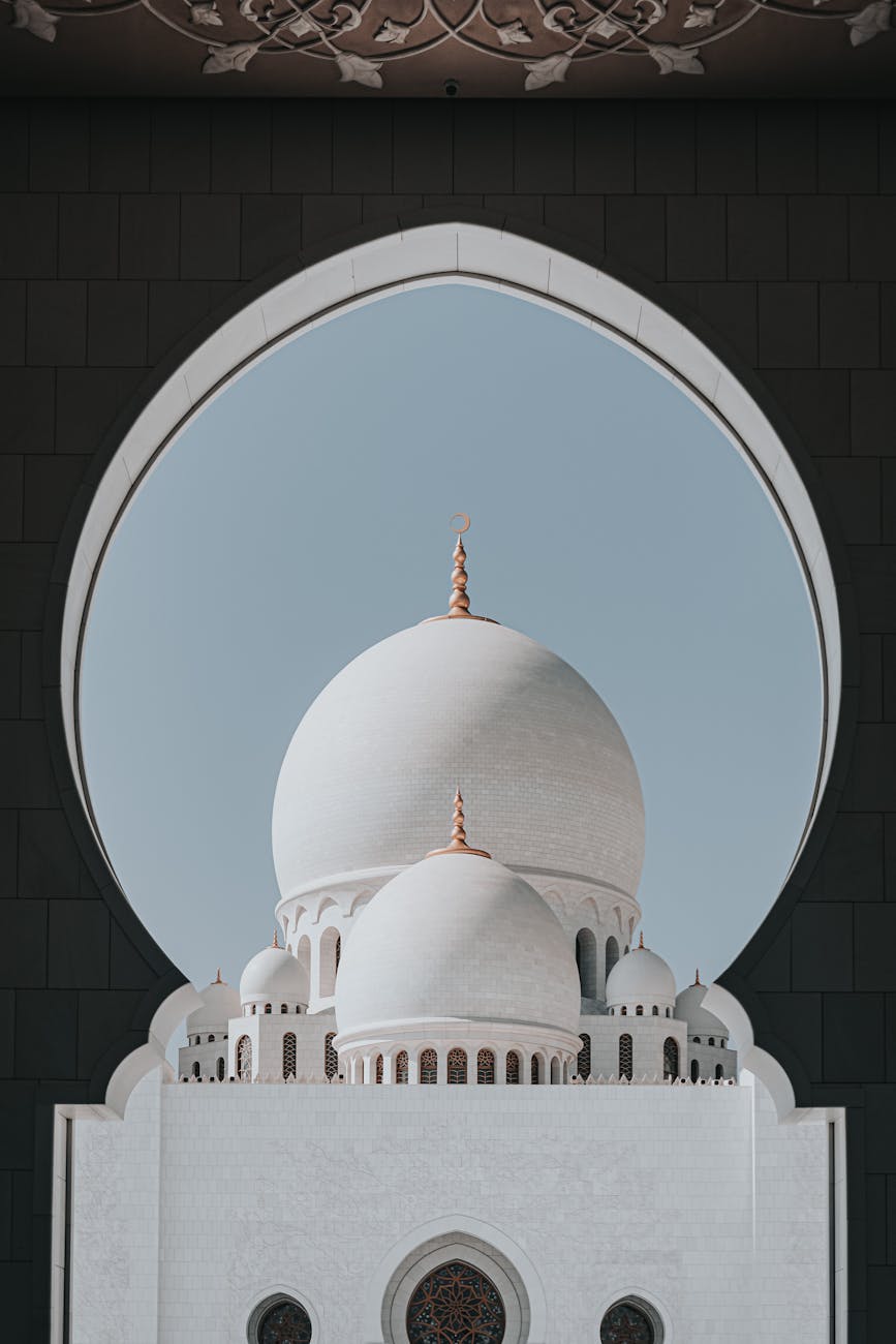 Elegant view of the Sheikh Zayed Grand Mosque dome framed by an arch in Abu Dhabi, UAE.