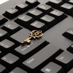 Close-up of an ornate vintage key placed on a modern computer keyboard.