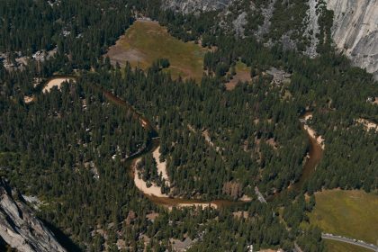 Stunning aerial shot of Yosemite Valley's lush forest and winding river, showcasing nature's beauty.