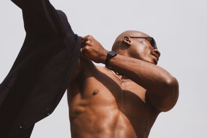 Athletic man with sunglasses posing outdoors, showcasing strength and style in Lagos.