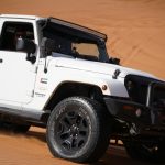 White Jeep Wrangler traversing desert dunes showcasing a thrilling off-road adventure.