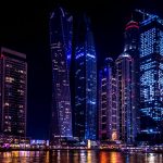 Illuminated skyscrapers of Dubai Marina at night, reflecting on the water.