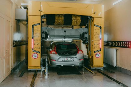 A car undergoing a wash in a modern, automated car wash station indoors.