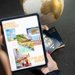 Traveler planning a trip to Italy and Switzerland using a globe, tablet, and passports.