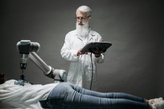 A scientist controls a robotic arm conducting research on a person lying down.