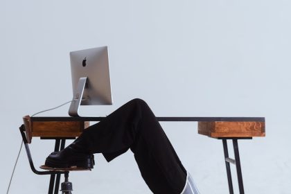 Woman in an innovative stretch position under an office desk, blending flexibility with workplace setting.