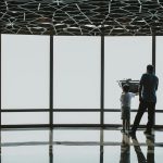 Silhouette of a father and child looking through a telescope at Burj Khalifa observation deck.
