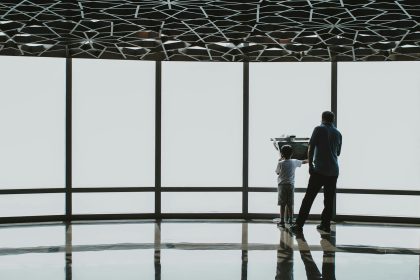 Silhouette of a father and child looking through a telescope at Burj Khalifa observation deck.
