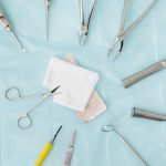 Top view of assorted dental surgical instruments on a blue background, sterile and ready for use.