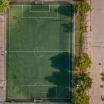 An aerial shot of a football and tennis court in Dubai, surrounded by trees.