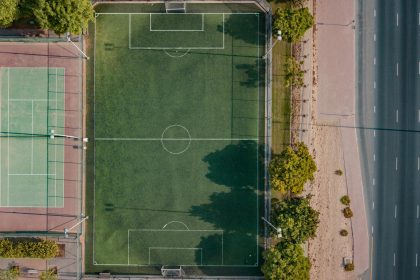 An aerial shot of a football and tennis court in Dubai, surrounded by trees.