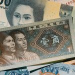 Vertical shot of various international banknotes displaying diverse currencies and designs.