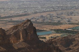 Breathtaking view from the mountains showcasing an arid landscape and a city below.