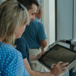 Tourists explore an interactive display at an observation deck, offering panoramic city views.