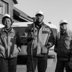 Three professional cleaners in uniform pose with equipment in front of a building.