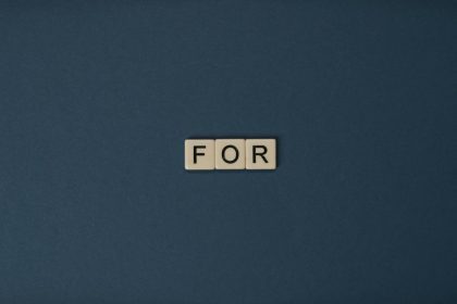 Artistic display of Scrabble tiles spelling the word 'For' on a dark background.