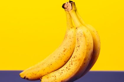 A bunch of fresh bananas isolated against a vibrant yellow and purple background.