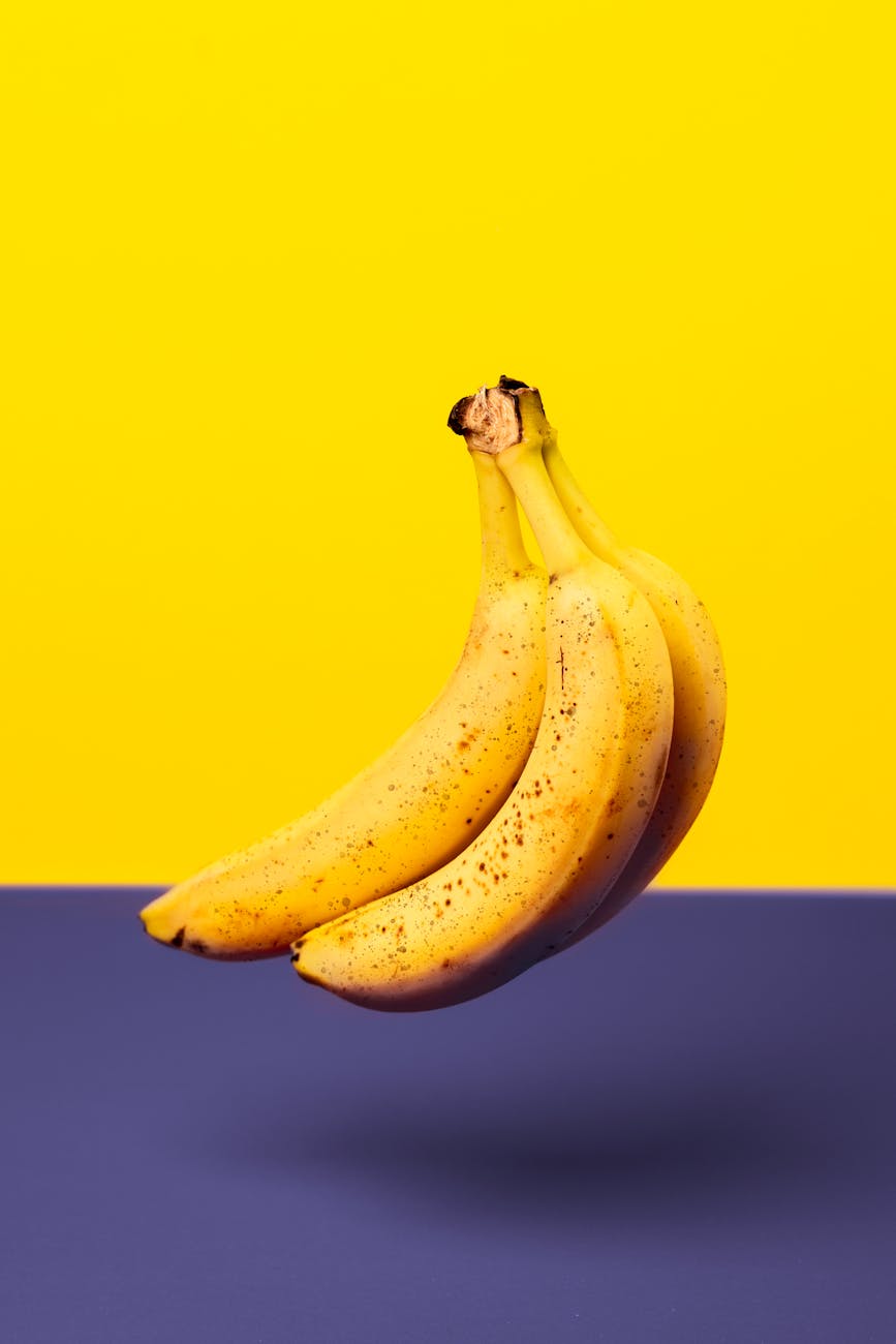 A bunch of fresh bananas isolated against a vibrant yellow and purple background.