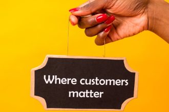 Hand holding a sign with 'Where customers matter' on a vibrant yellow backdrop.
