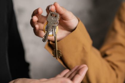 Two adults exchanging house keys, symbolic of property transfer or rental agreement.