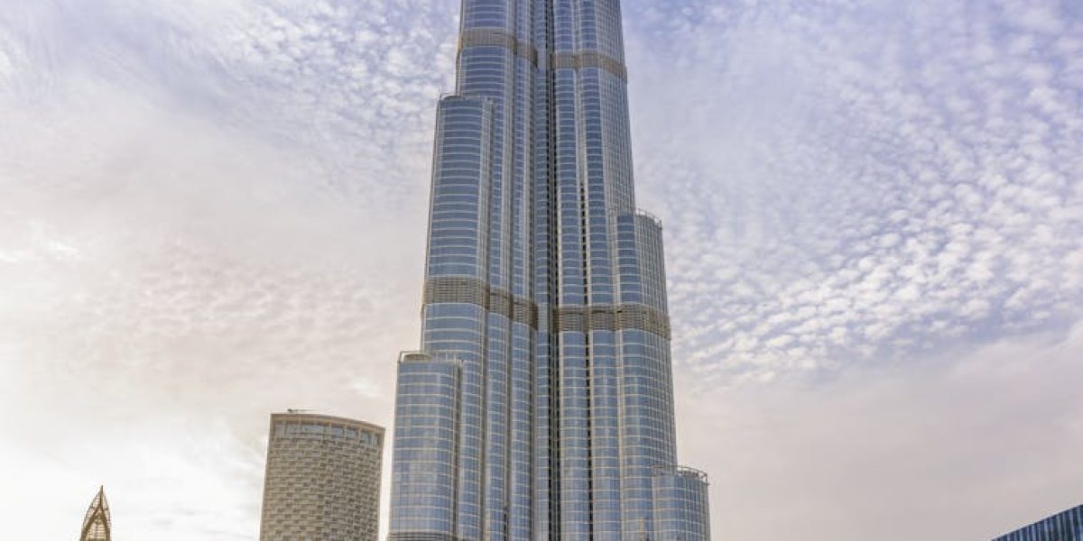 Majestic Burj Khalifa against a bright blue sky reflecting in water, Dubai.