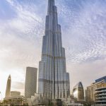 Majestic Burj Khalifa against a bright blue sky reflecting in water, Dubai.