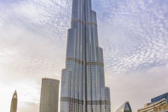 Majestic Burj Khalifa against a bright blue sky reflecting in water, Dubai.
