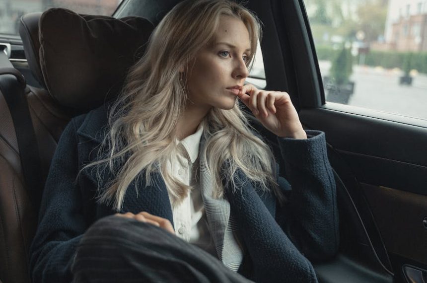 A thoughtful businesswoman sits in a luxurious car, pondering during a ride.